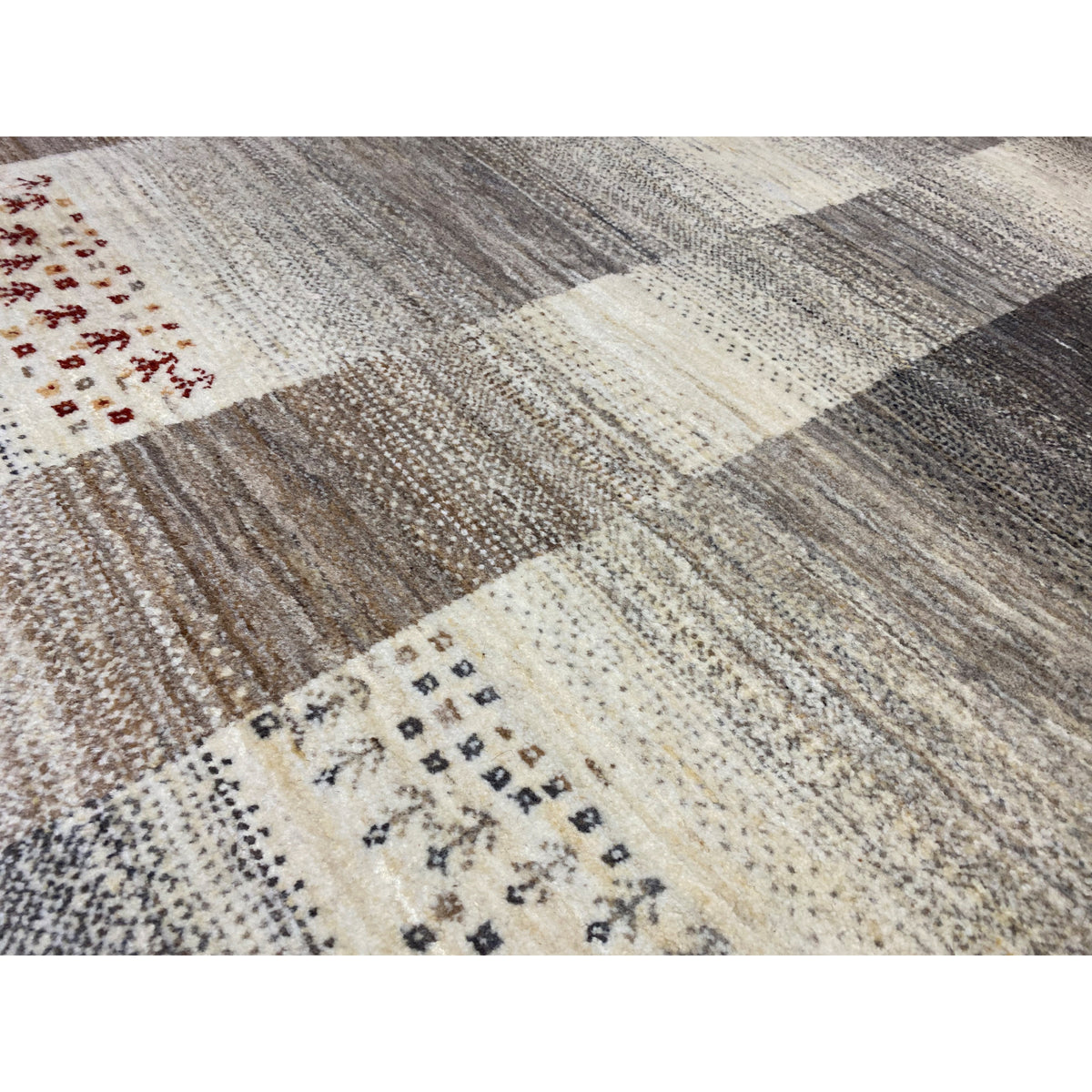 Gabbeh rug close-up: textile texture, block pattern in cream and gray with red motifs