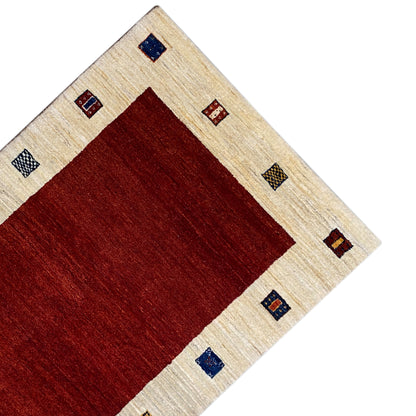 Rug corner with a red center, beige border, and multicolored decorative squares