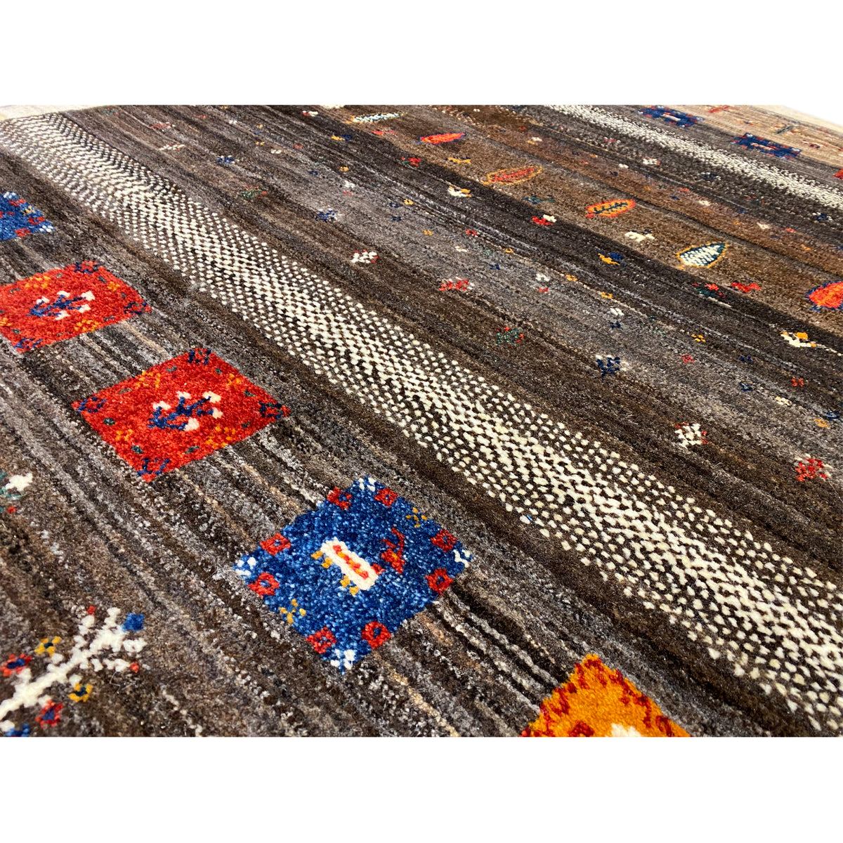 Carpet detail: brown-gray fiber strips with colorful square patterns and a beige border.