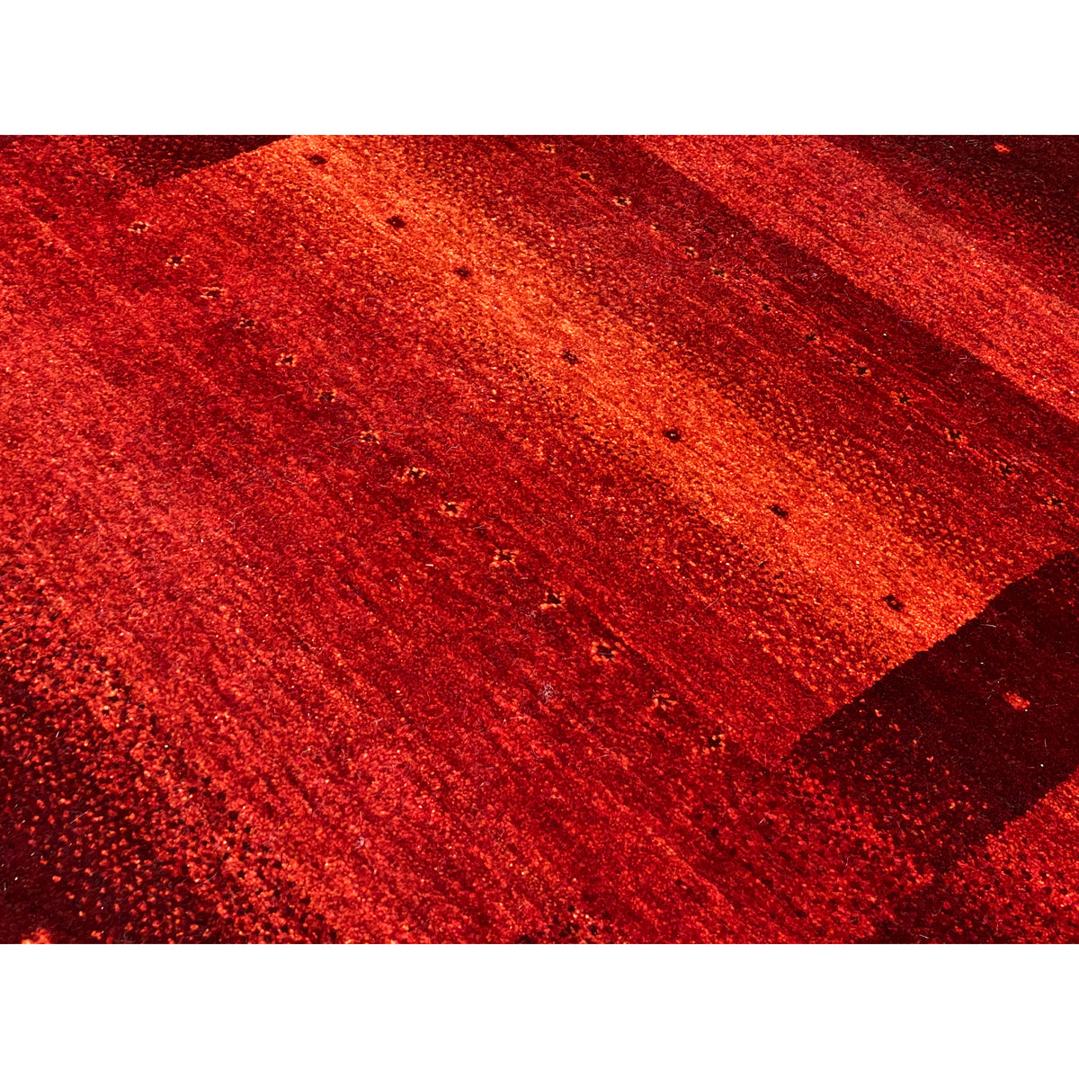 Gabbeh rug detail, red-orange surface with an even texture