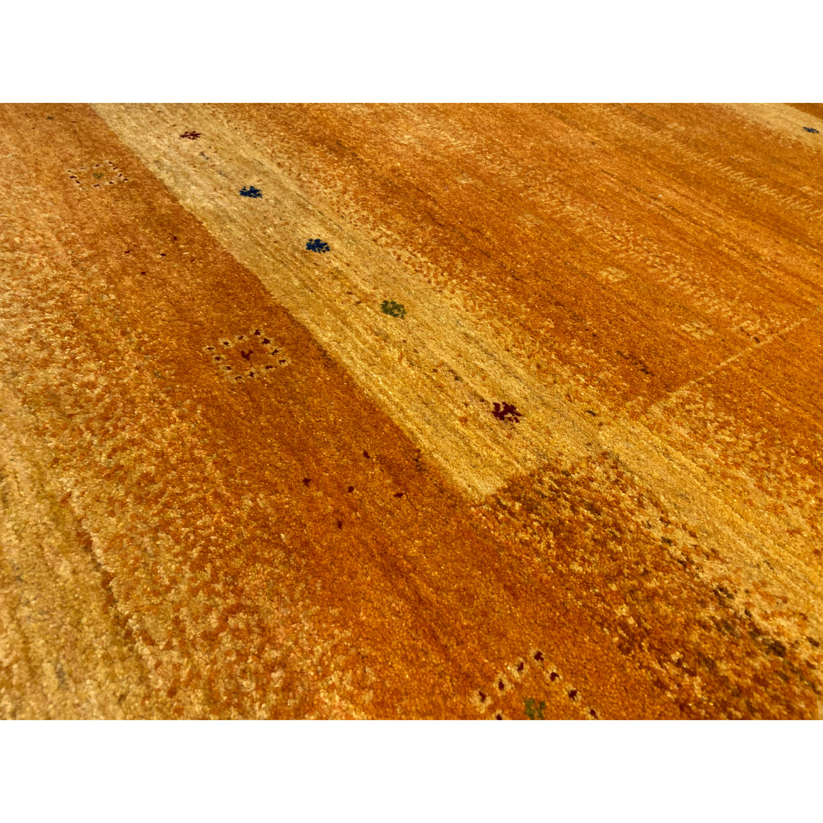 Close-up of a honey-brown Gabbeh rug with a matte texture and small multicolored accents