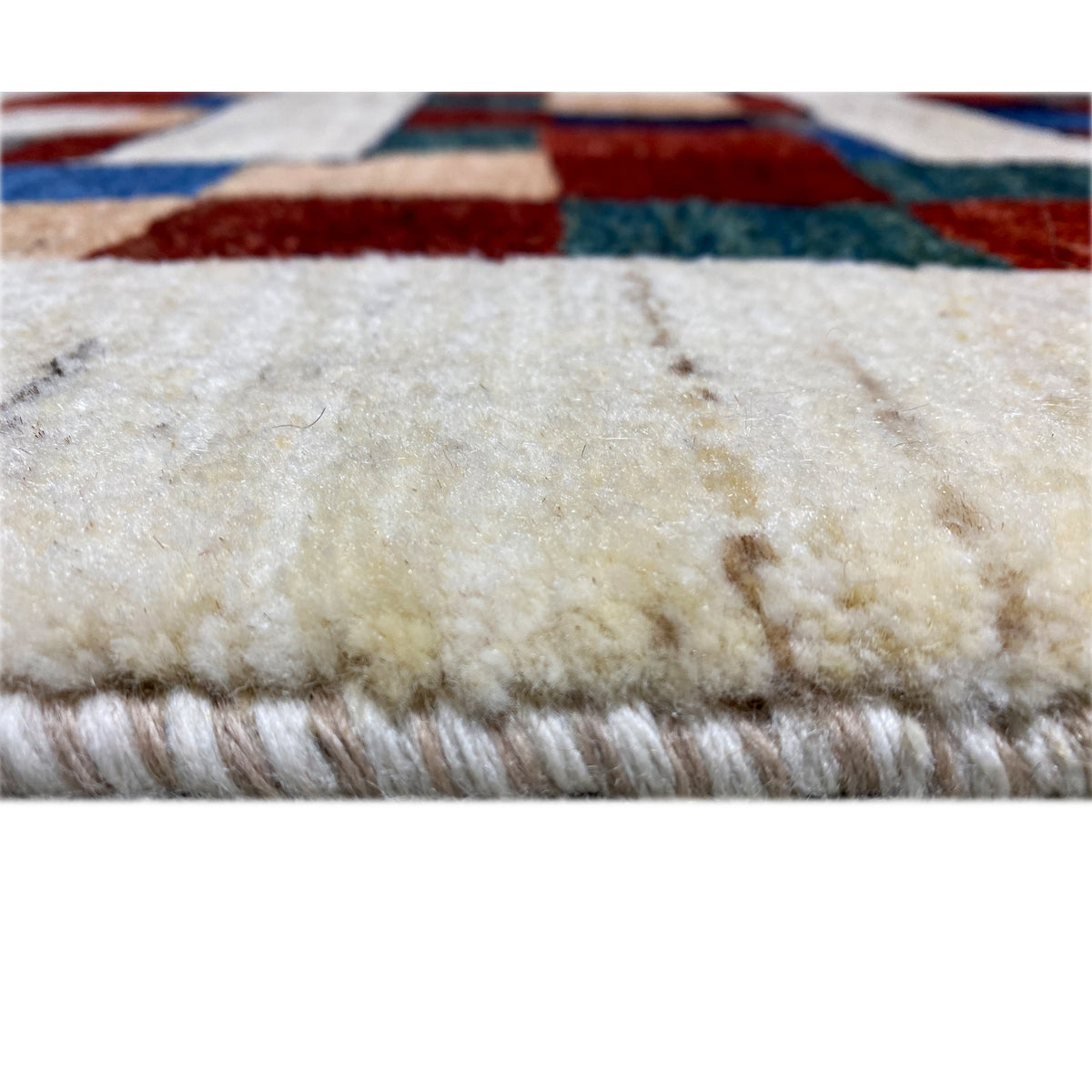 Gabbeh rug close-up of the pile height, cream-colored textile with multicolored edge stripes