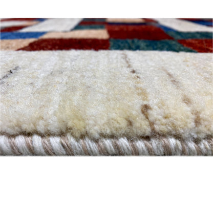 Gabbeh rug close-up of the pile height, cream-colored textile with multicolored edge stripes