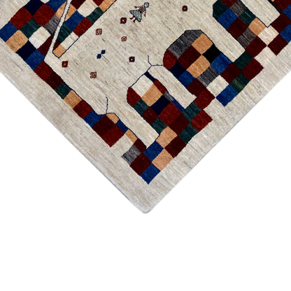 Gabbeh rug corner view: cream-colored pile with geometric squares in blue, red, and green