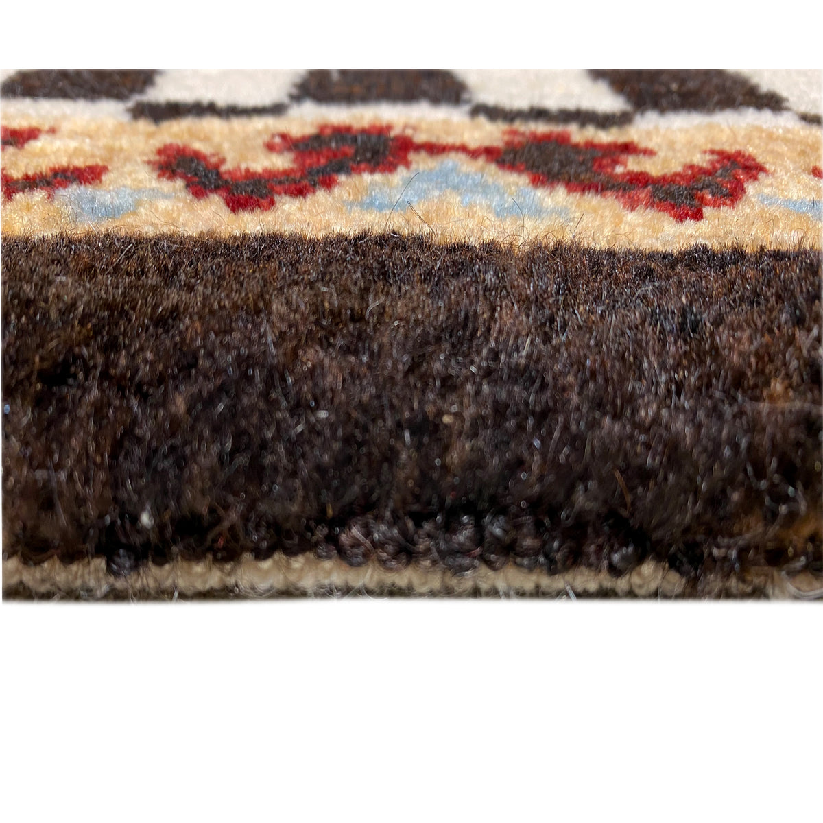 Rug edge in detail: dense pile with a brown border and multicolored stripes at the top