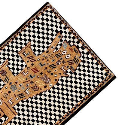 Corner view of a Gabbeh rug: black-and-white squares, beige motif in the center, brown border