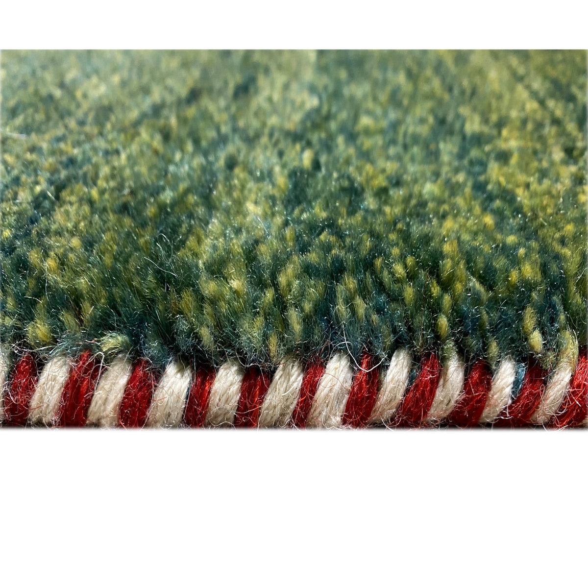 Close-up of a Gabbeh rug with a green pile and a striped border of red and white fringes
