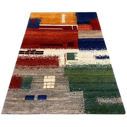 Gabbeh rug 186x125 cm shown at an angle, abstract patchwork pattern in shades of red, blue, and green