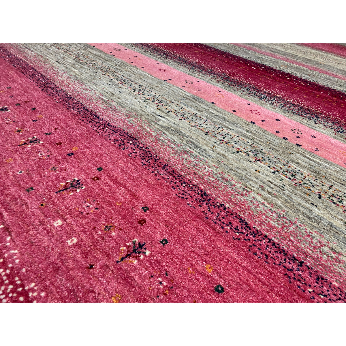 Close-up of the Gabbeh rug: mottled texture, fine dots in the pink-gray pattern
