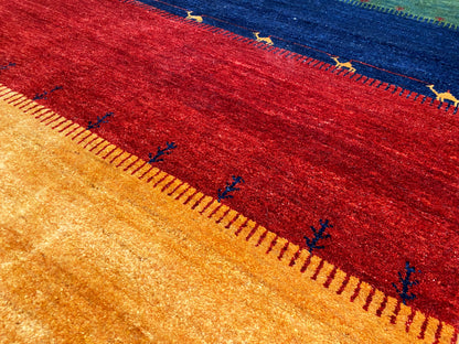 Teppichstreifen im Nahblick: Rot und Ocker mit feinem Muster entlang der farbigen Kante.