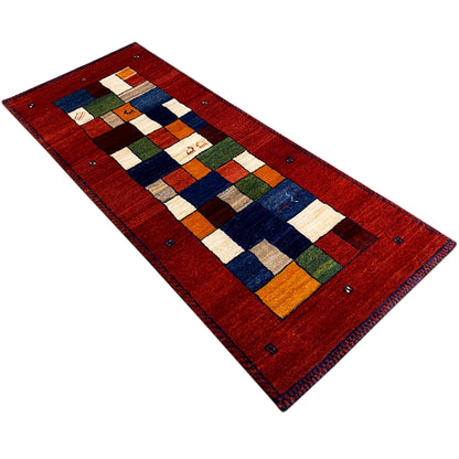 Red Gabbeh runner rug positioned diagonally with a colorful square design and fringed edges