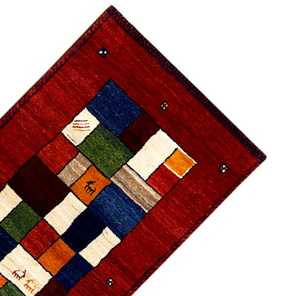 Corner of a red Gabbeh runner rug with a blue-green square motif and decorative border