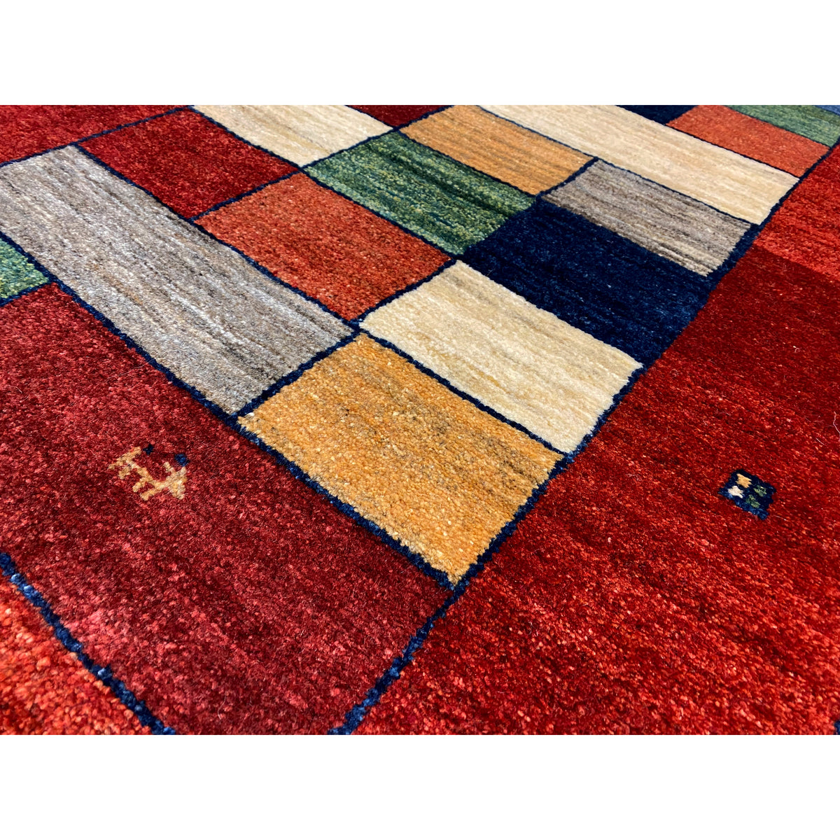 Detail of the Gabbeh runner rug: red with a block mosaic in cream, green, and blue tones