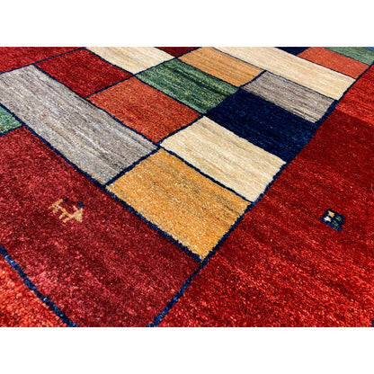 Detail of the Gabbeh runner rug: red with a block mosaic in cream, green, and blue tones