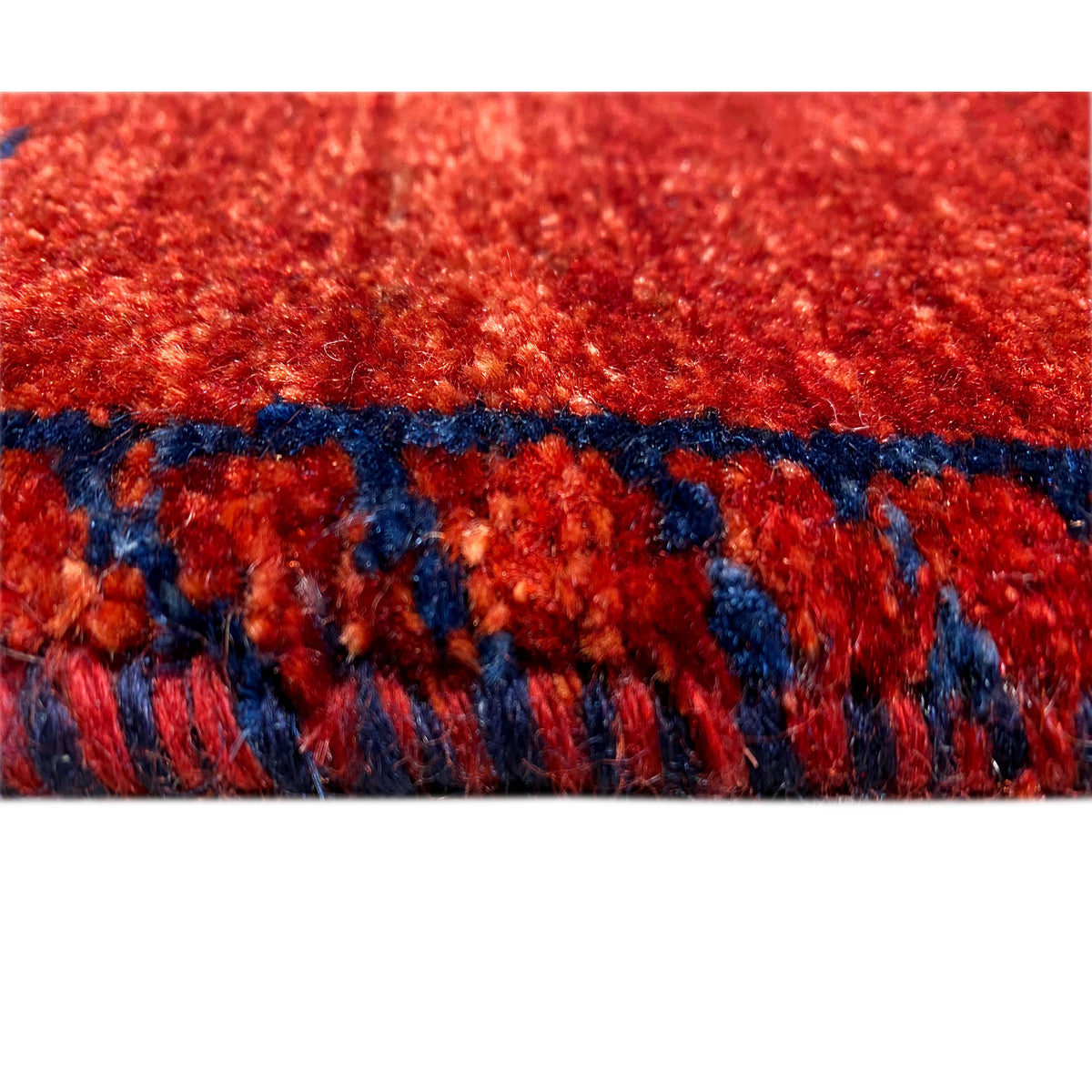 Close-up of the pile and border: red with a blue patterned frieze along the lower edge