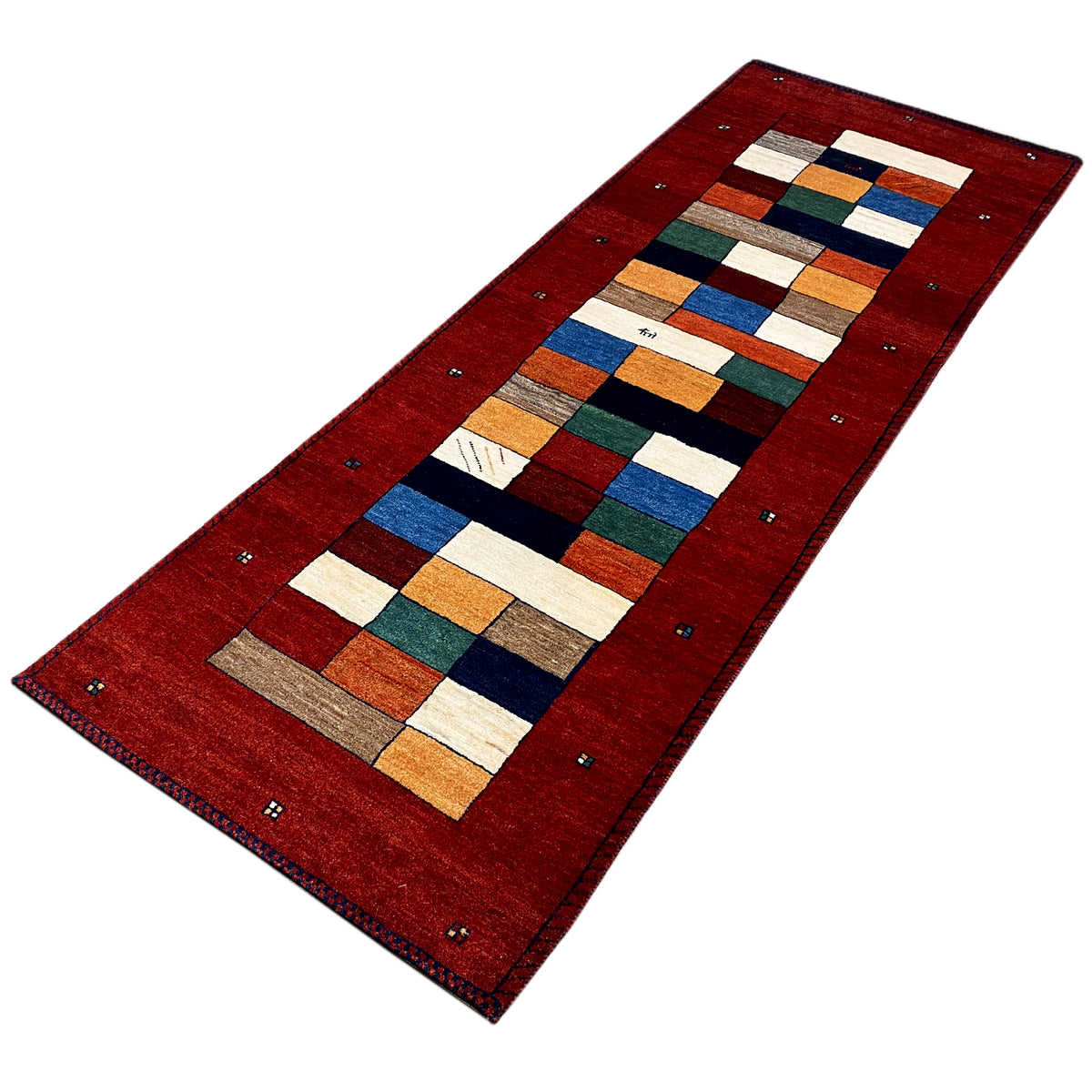 Red Gabbeh runner rug viewed at an angle, rectangular pattern and surrounding border