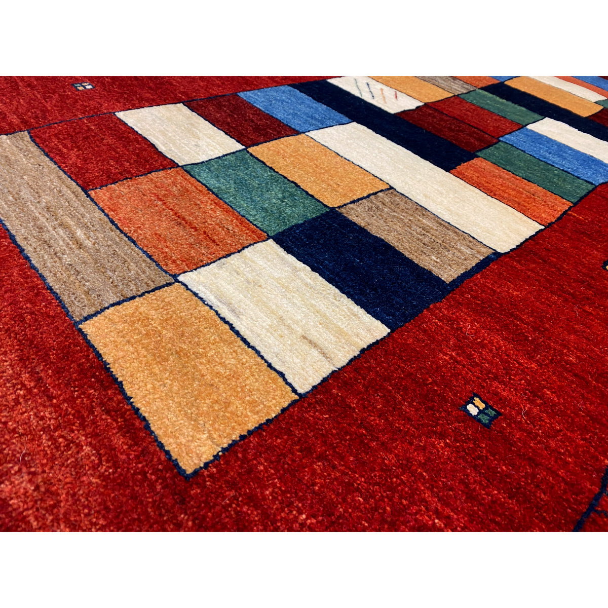 Close-up: red Gabbeh runner with multicolored squares and a fine pile surface