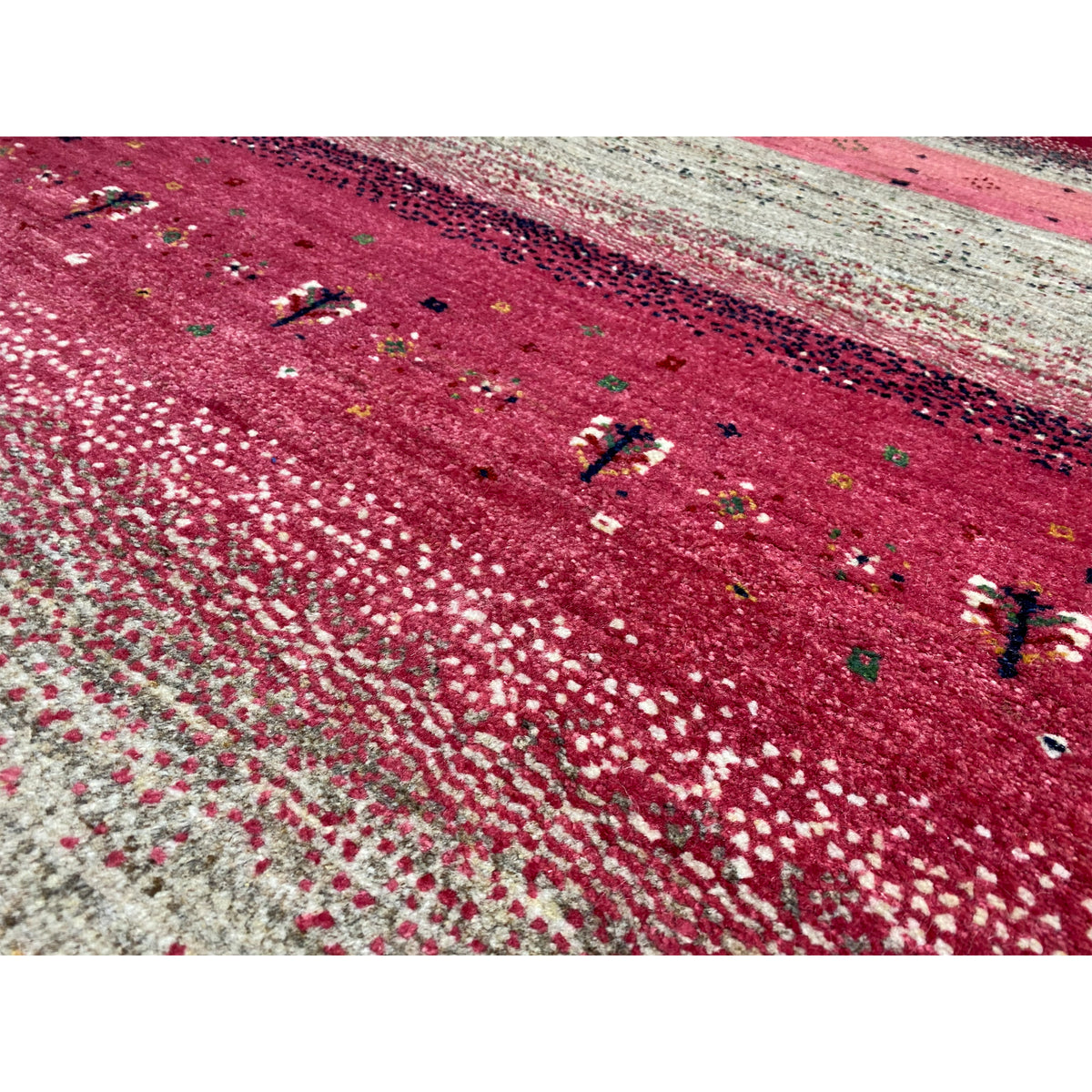 Close-up of a Gabbeh rug: burgundy surface with beige dots and delicate embellishments