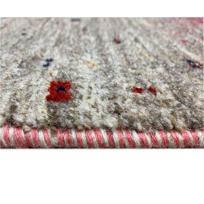 Close-up of the edge of a Gabbeh runner rug with a beige pile and colorful accents