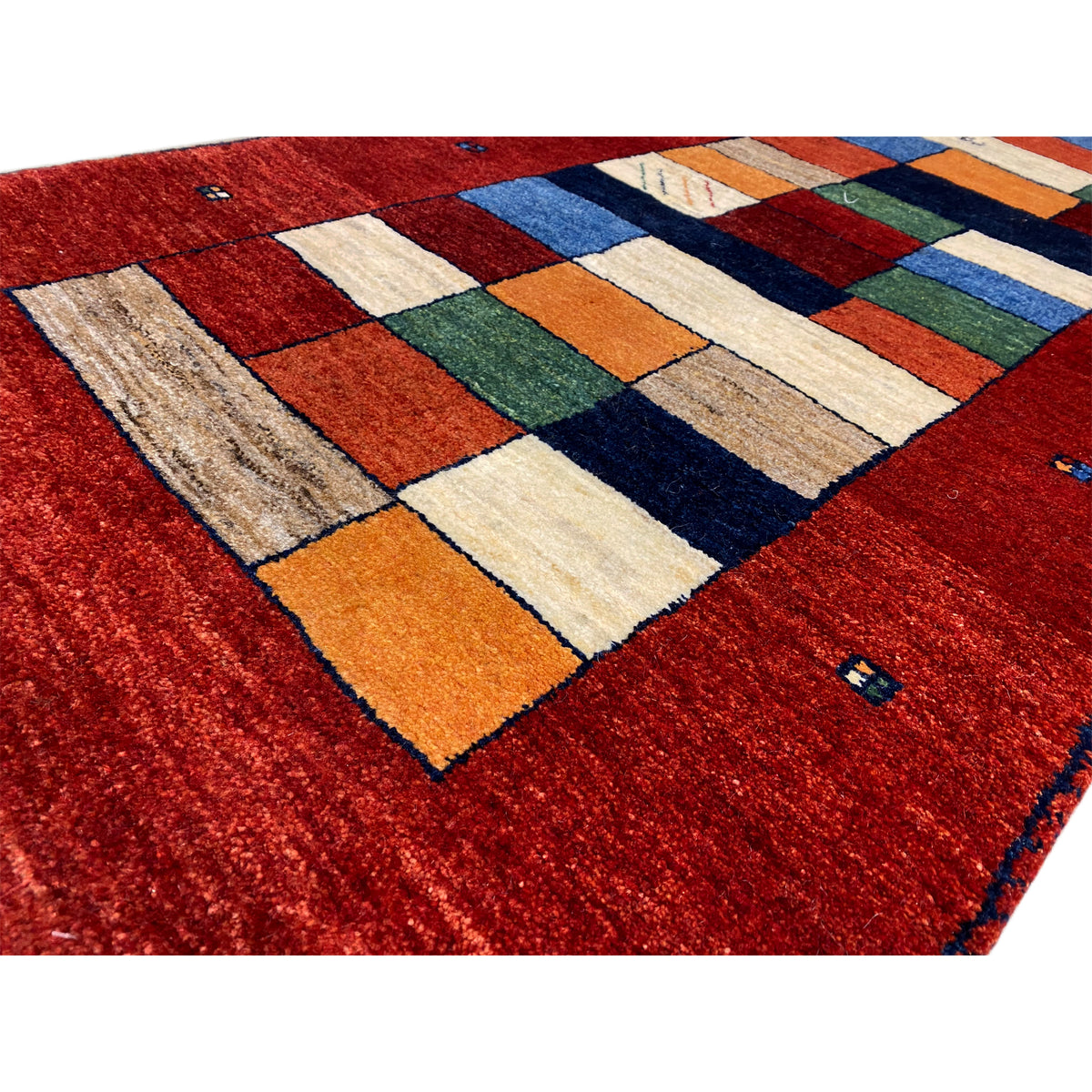 Gabbeh runner rug detail: red area with a colorful square pattern and a nubby edge