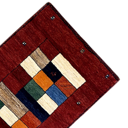Gabbeh rug runner corner with red pile, multicolored central ornament, and small dots