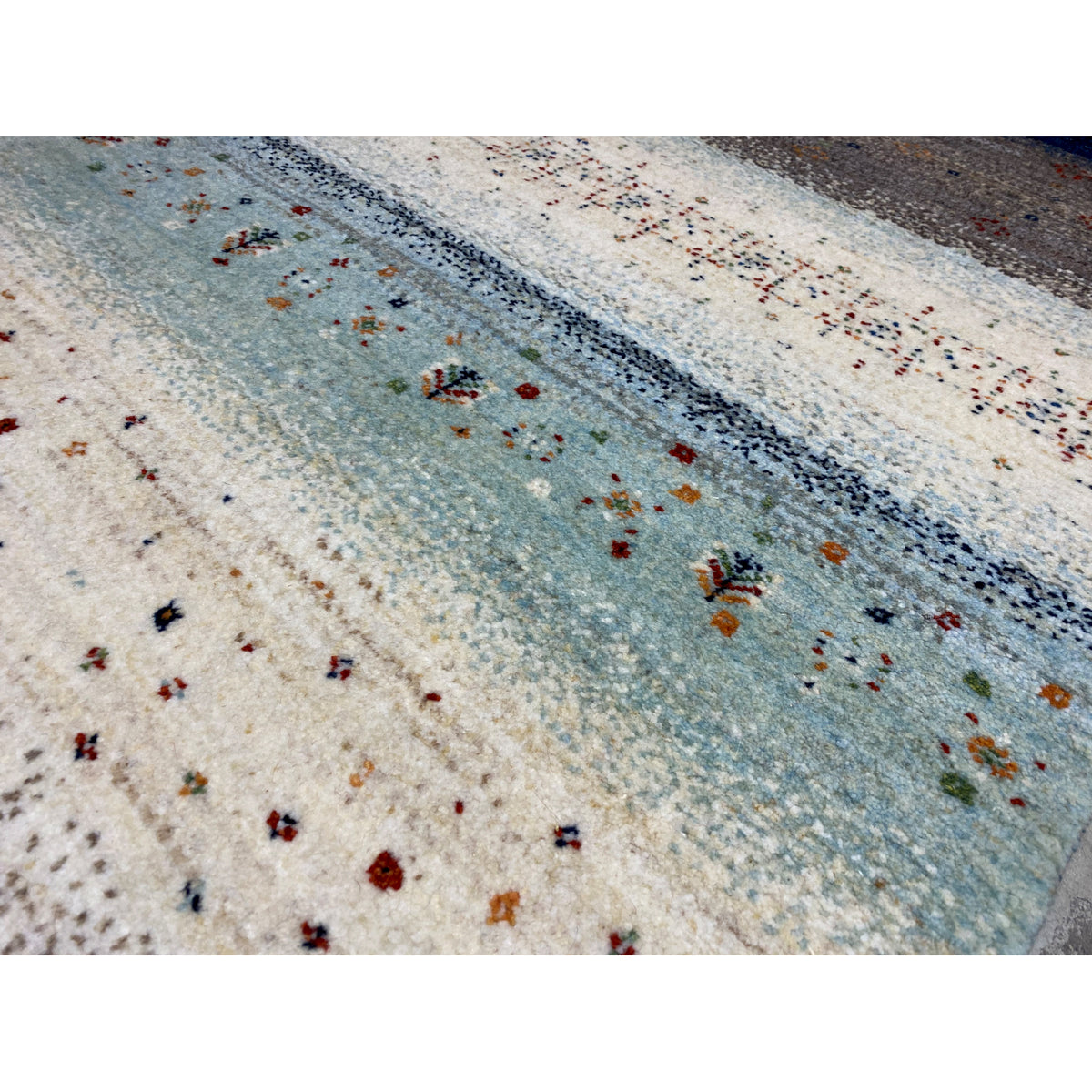 Gabbeh rug runner close-up: blue-gray stripe on a light background with colorful dots