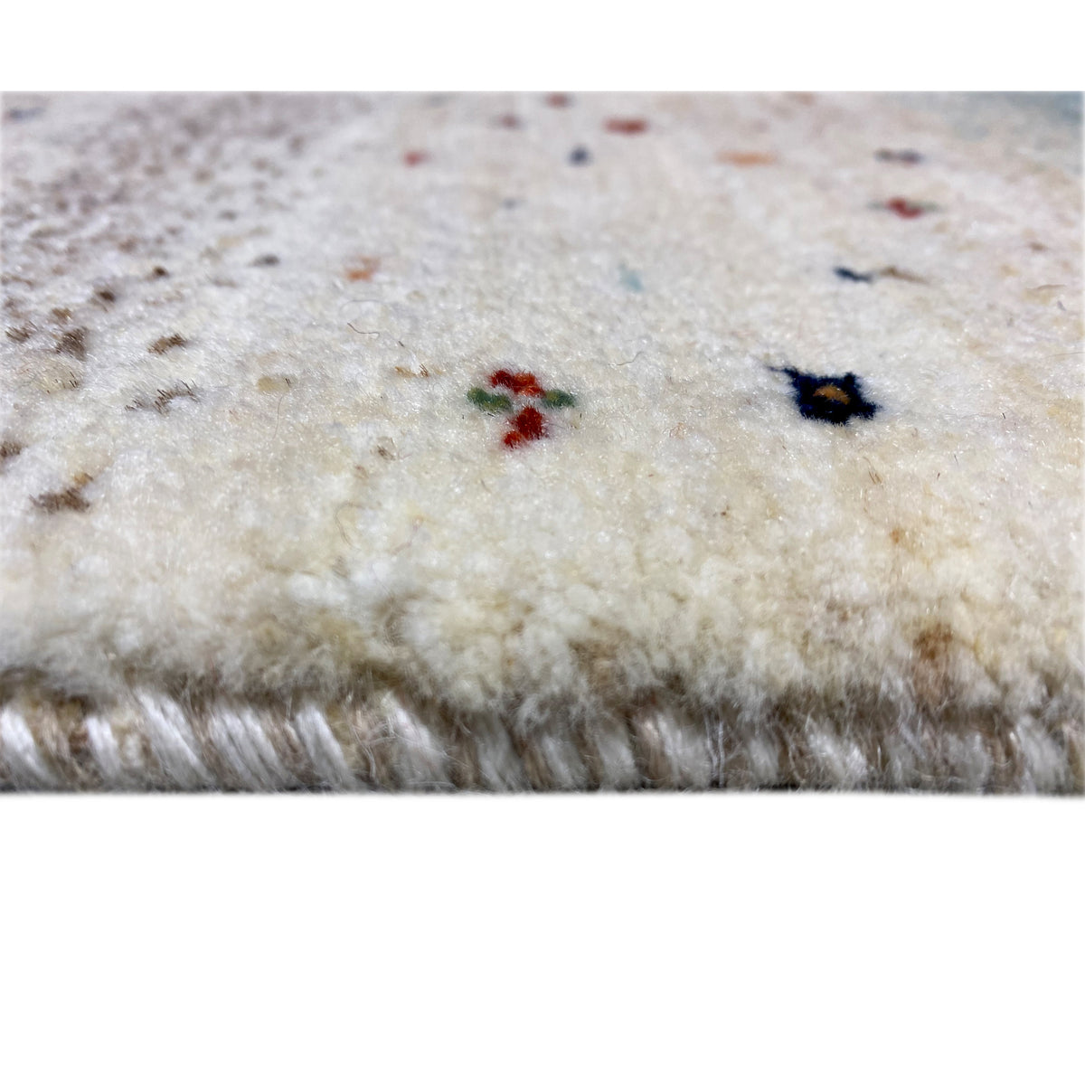 Gabbeh runner rug detail: short pile on a light background with colorful accents and fringes