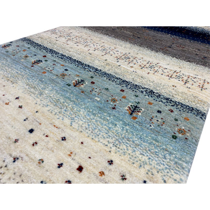 Close-up of a Gabbeh runner rug: light surface with a blue band and delicate embroidered patterns