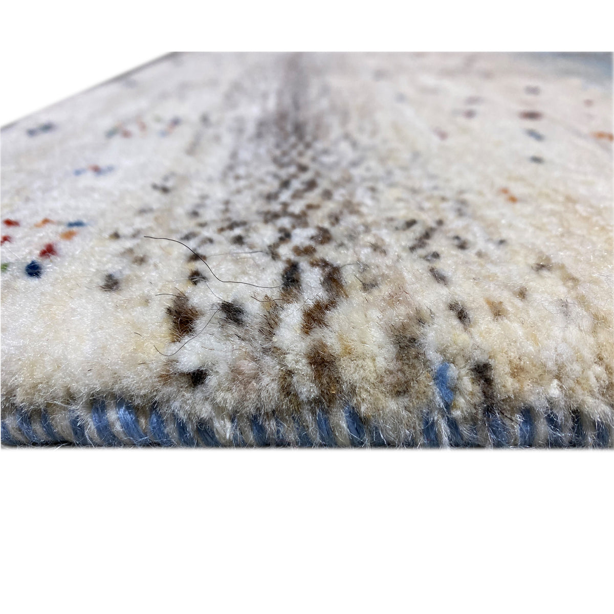 Detail of Gabbeh runner rug: pile with flecked texture and blue-gray border along the edge