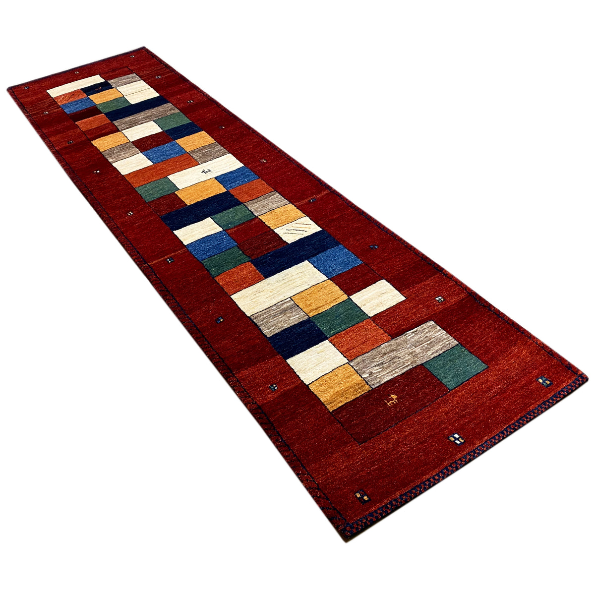 Red Gabbeh runner rug viewed at an angle with geometric blocks in blue, green, and yellow