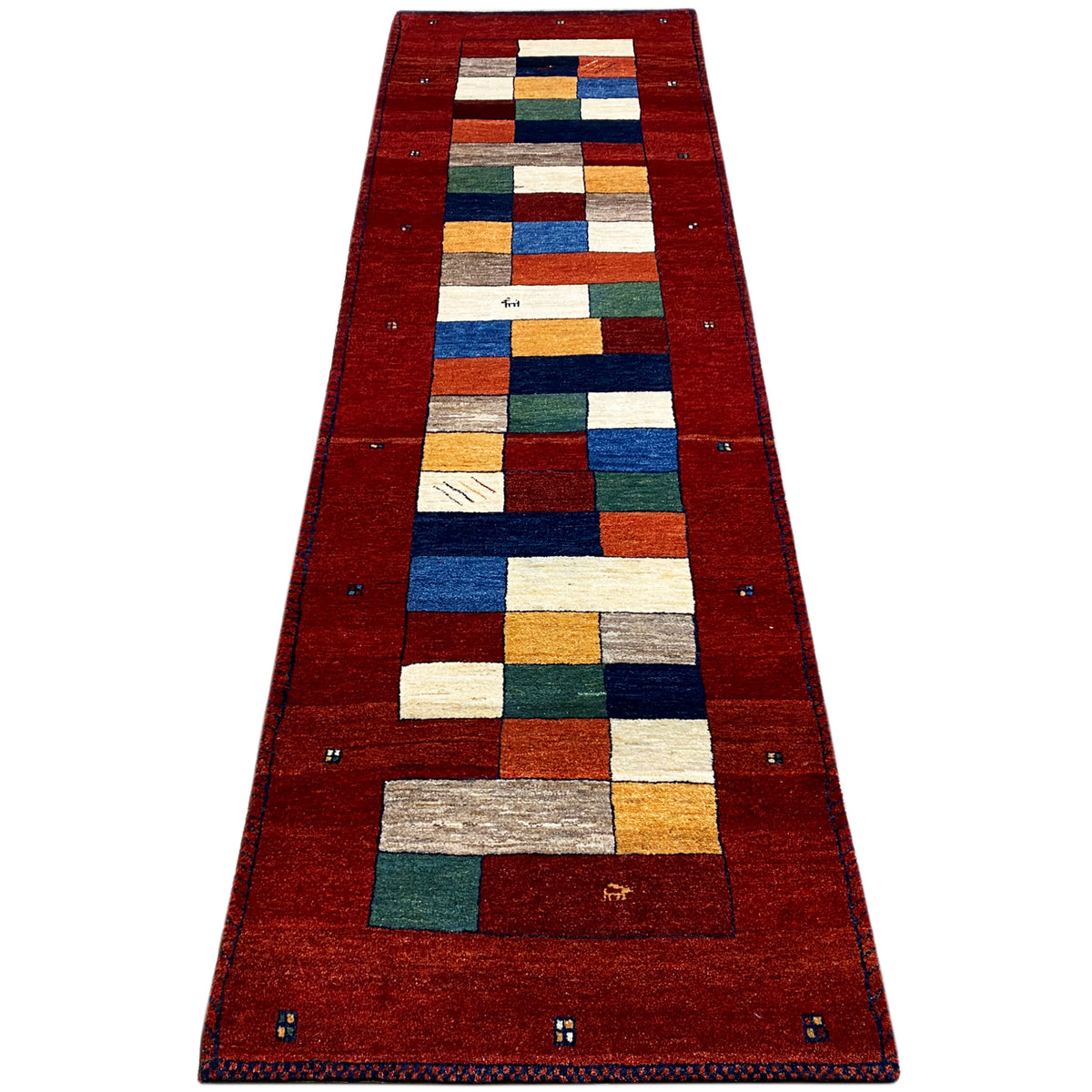 Red Gabbeh runner rug with geometric patchwork in red, blue, and green.