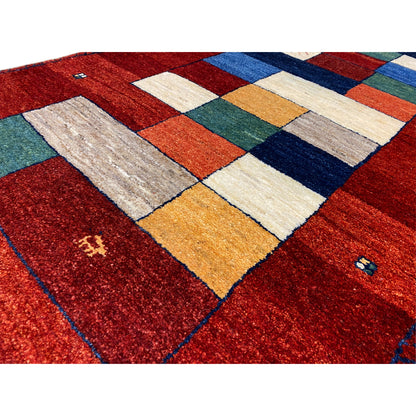 Close-up of a red Gabbeh rug runner: dense pile, multicolored squares.