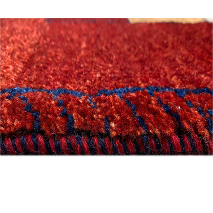 Red Gabbeh runner rug with fringes and blue trim along the edge.