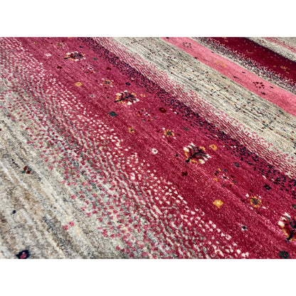Close-up of a Gabbeh rug: red and pink striped pattern with beige and black speckles