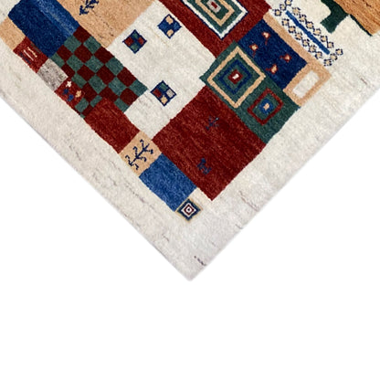 Gabbeh rug corner detail: geometric ornaments in blue, red, and beige on light-colored areas