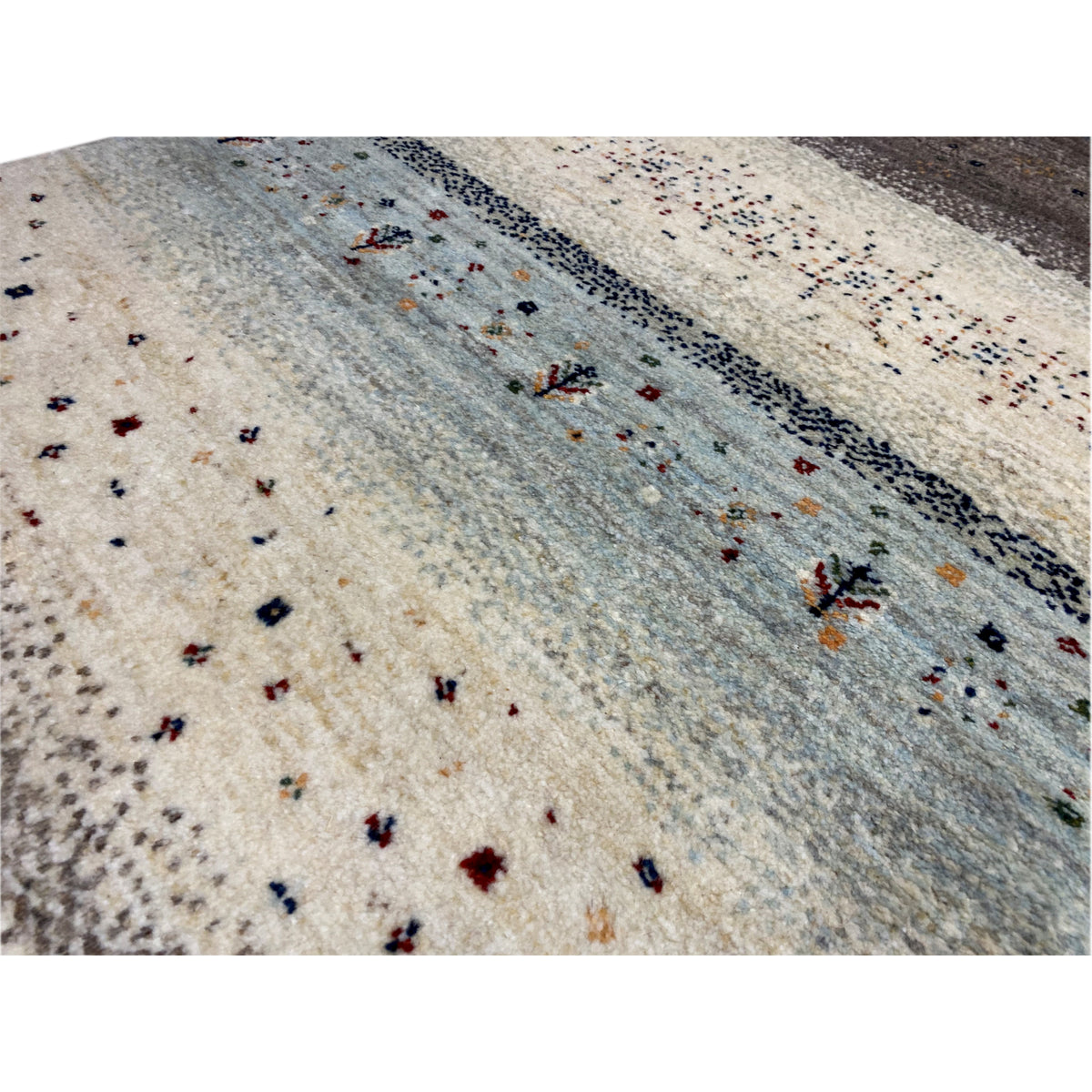 Close-up: Gabbeh rug runner with a light beige background, blue-gray zone, and fine dot patterns