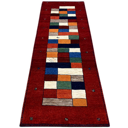 Red carpet runner with multicolored square and rectangular patterns in the central strip and border
