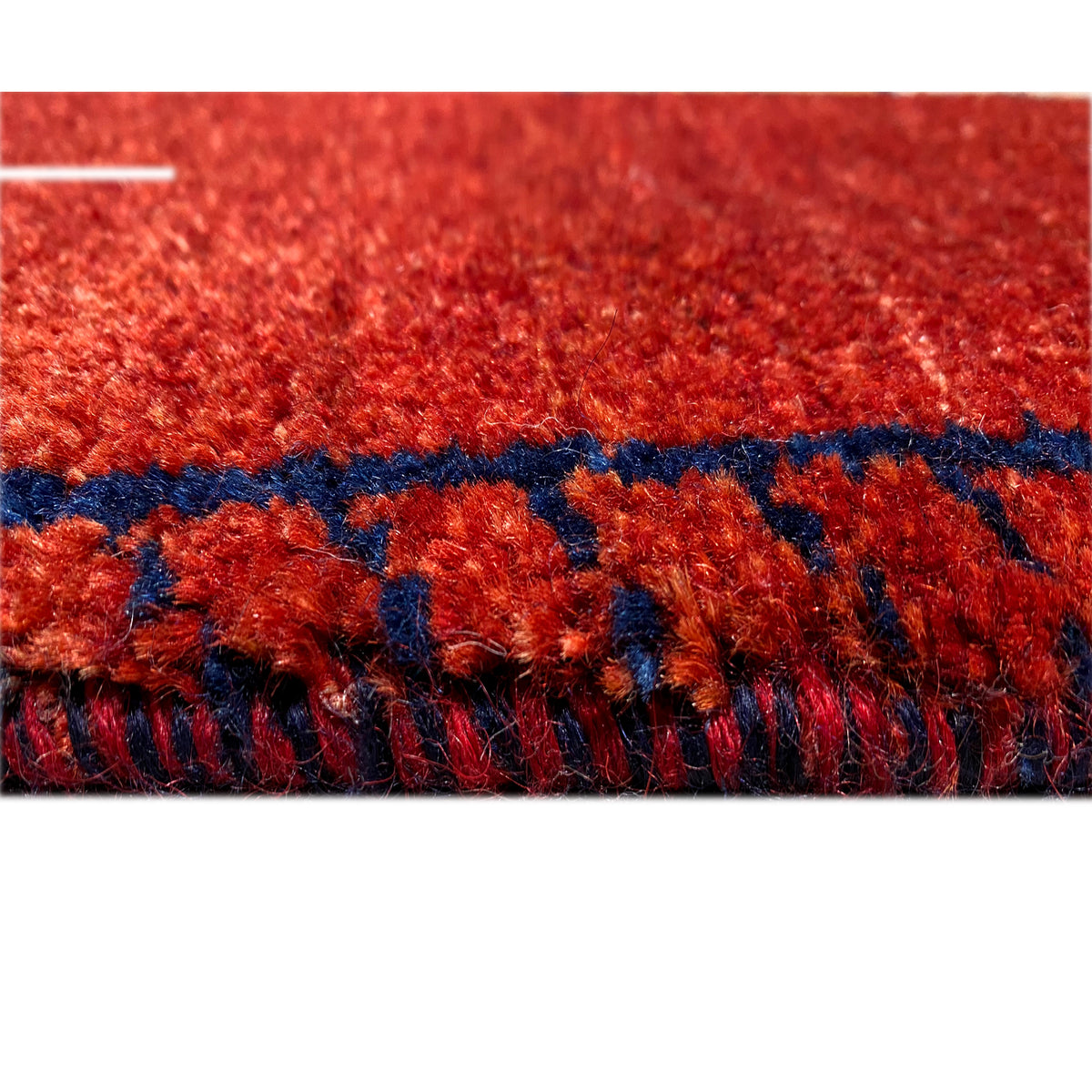 Close-up of the carpet surface: red pile with colored threads and a dark border strip