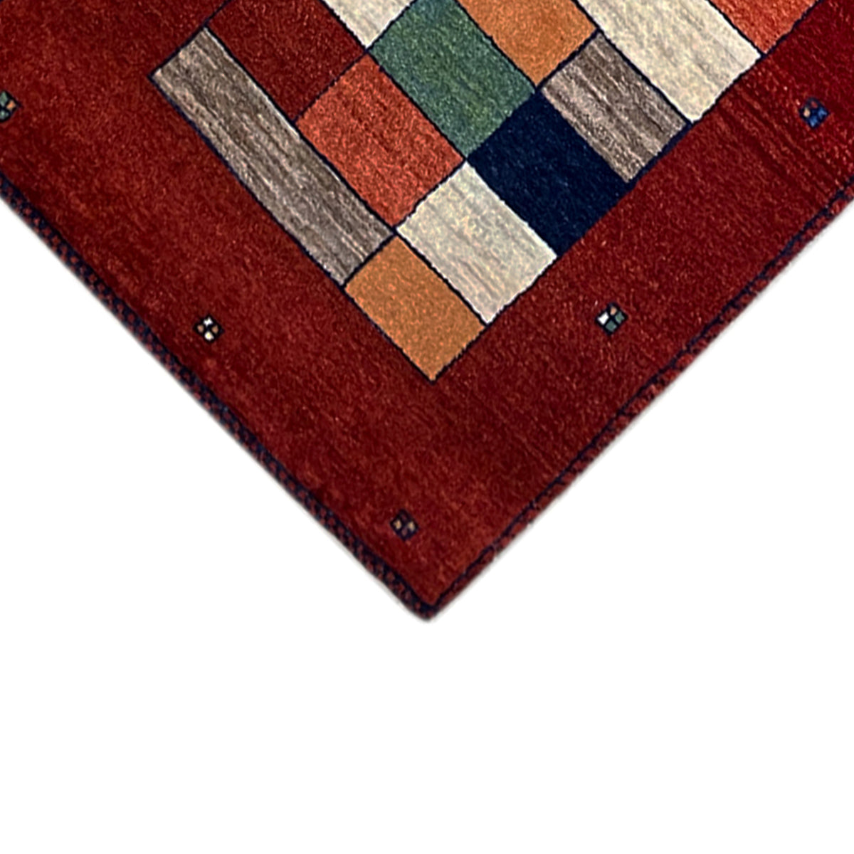 Close-up of the rug’s edge: red Gabbeh runner with colorful geometric blocks and decorative dots