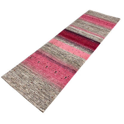 Gabbeh runner rug laid at an angle, with high-contrast stripes in pink and gray featuring patterned dots.