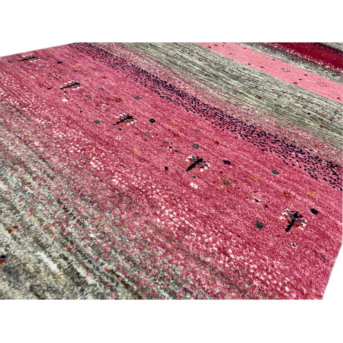 Close-up of a Gabbeh runner rug: pink surface with shiny threads and small dots.