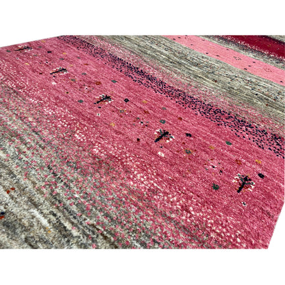Close-up of a Gabbeh runner rug: pink surface with shiny threads and small dots.