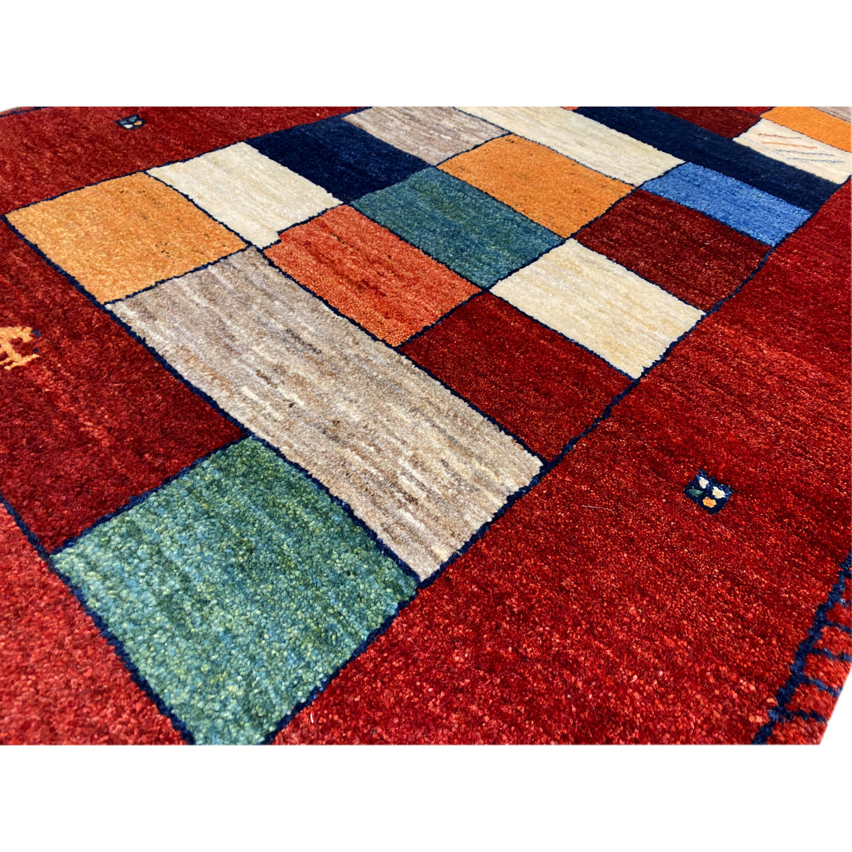 Close-up: red table runner with colorful patchwork pieces in blue, green, and orange