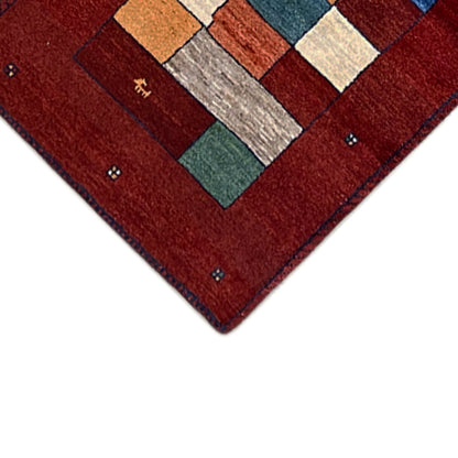Corner detail: red Gabbeh runner rug with decorative elements and dotted border