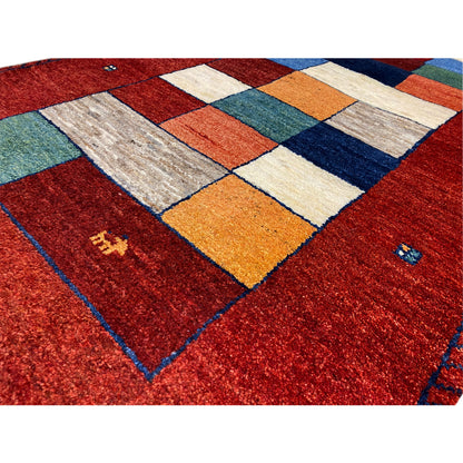 Close-up of a Gabbeh runner rug: red pattern with patchwork squares in yellow, blue, and green