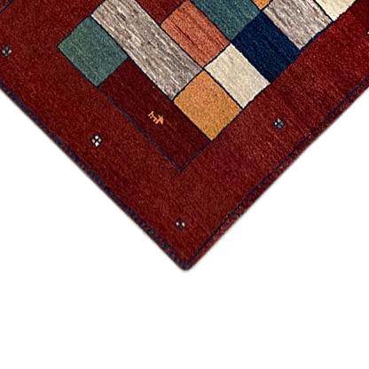 Gabbeh rug runner close-up of the corner: red border with a pattern in white, blue, and orange