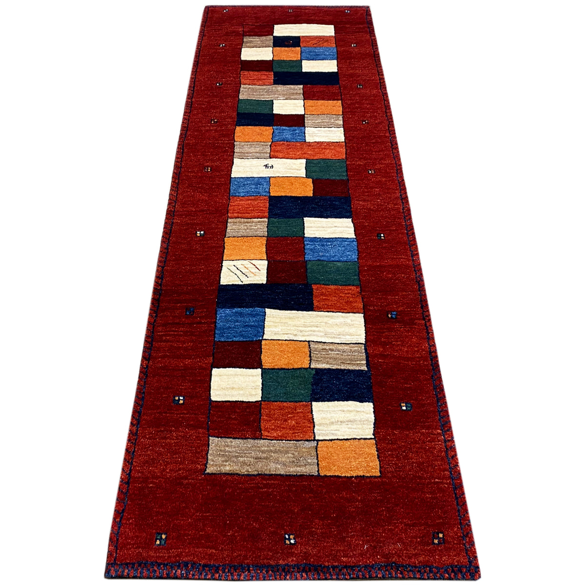Red Gabbeh runner rug laid lengthwise, patchwork squares in blue, green, and beige
