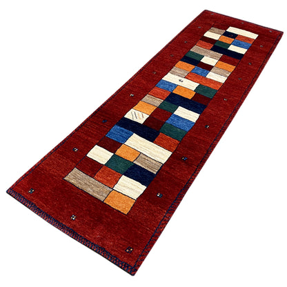 Red Gabbeh runner rug at an angle, geometric patchwork rectangular pattern made of squares