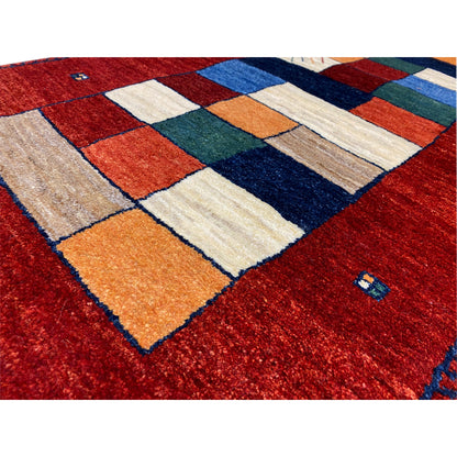 Close-up: red Gabbeh runner rug with patchwork squares in orange, blue, and beige