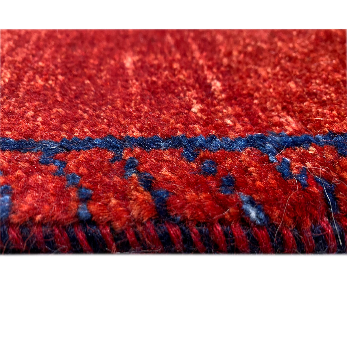 Detail: red Gabbeh runner rug with a blue decorative border and fringes